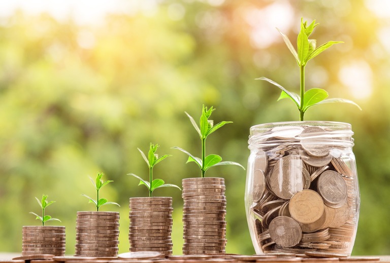 Three glass jars filled with coins and growing plants, illustrating investment in team capability and long-term sales growth.