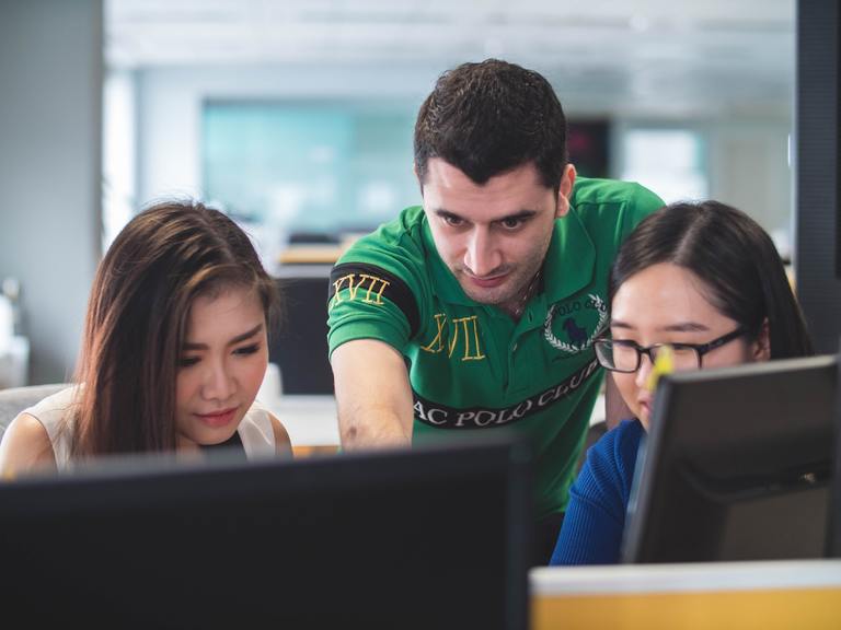 Young manager guiding a team at computer screens, reflecting onboarding actions and early leadership influence.