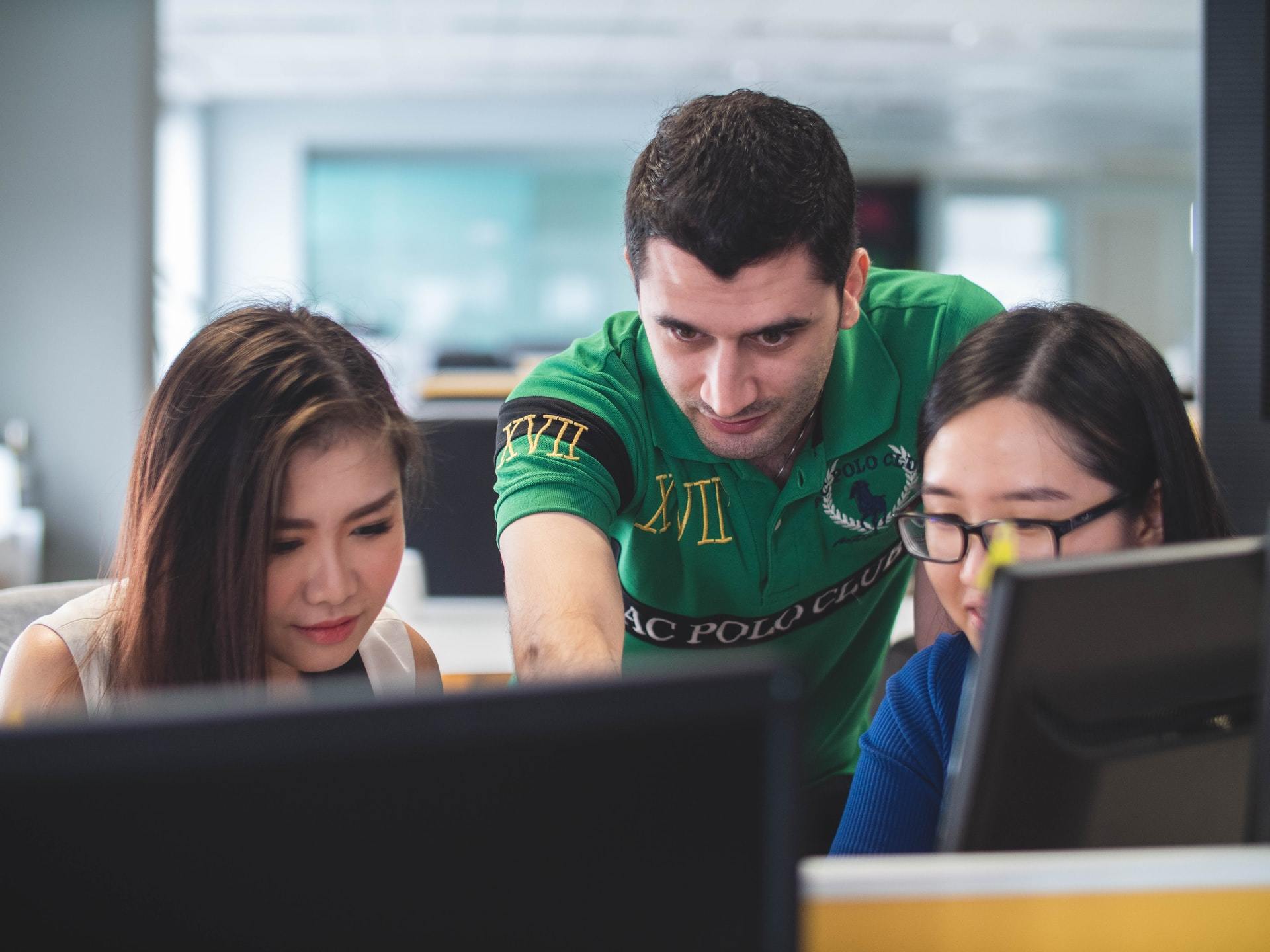 Young manager guiding a team at computer screens, reflecting onboarding actions and early leadership influence.