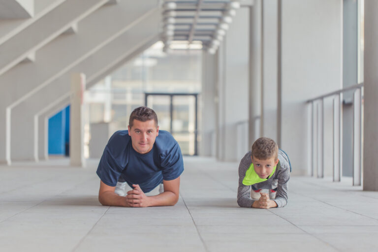 Adult and child doing planks in parallel, symbolising tailored coaching for both performance and long-term development.