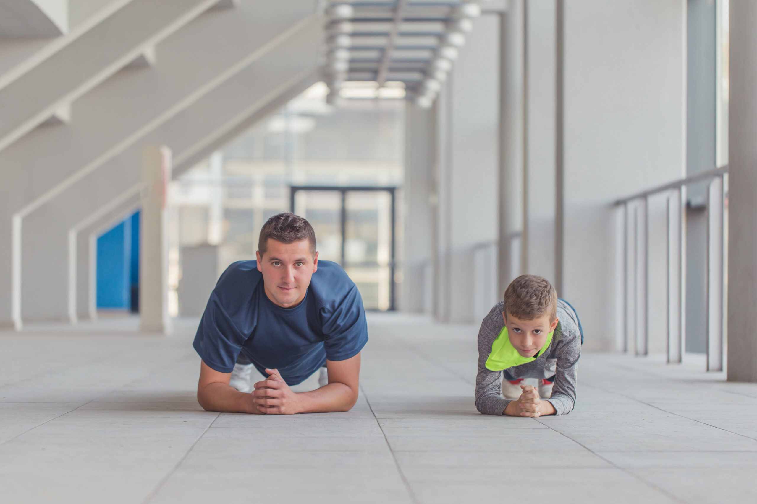 Adult and child doing planks in parallel, symbolising tailored coaching for both performance and long-term development.