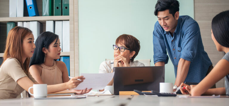 Sales team in a coaching conversation discussing strategy and performance improvement in a modern office setting
