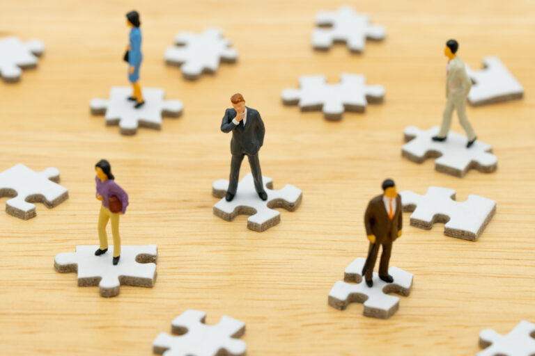Individuals standing on separate puzzle pieces, illustrating development that depends on individuals rather than a connected system