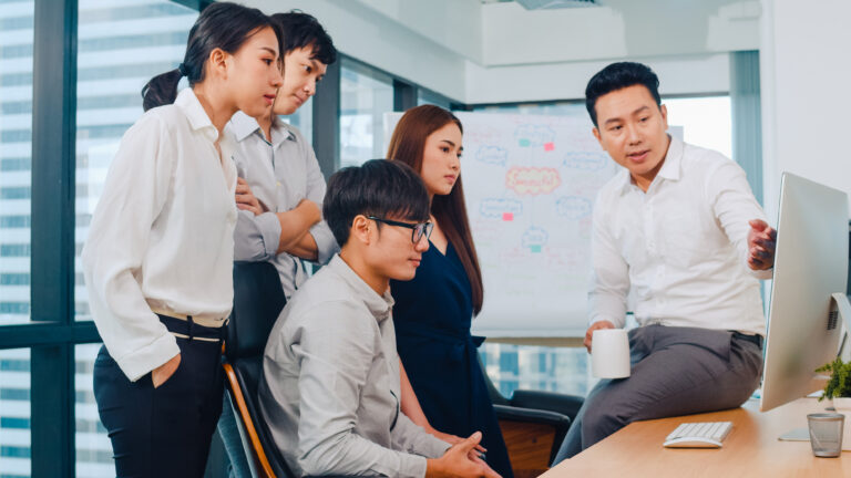 Sales manager discussing work priorities with the sales team during a busy office meeting